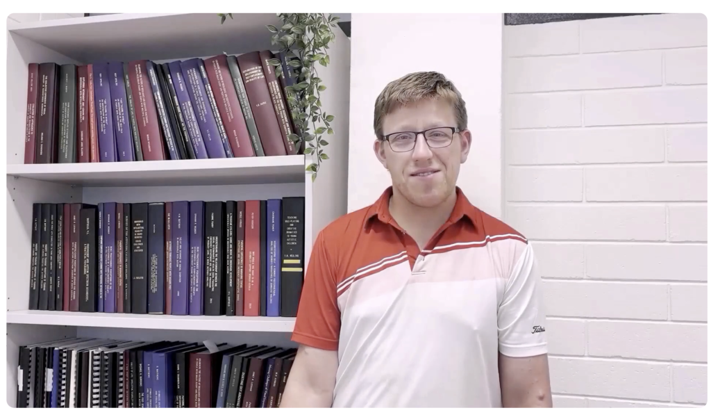 man talking infront of bookshelf to camera