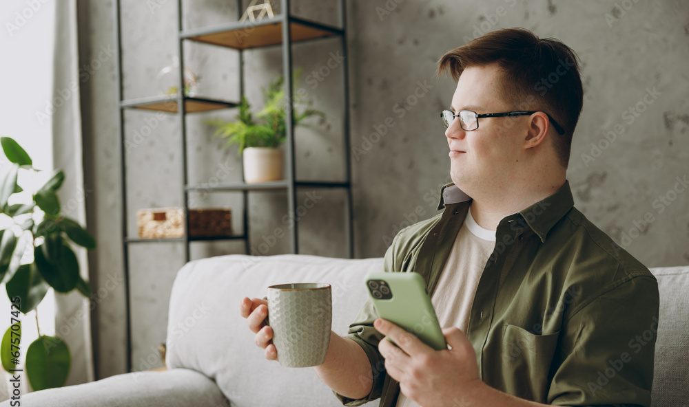 Young man using his phone and drinking a cup of coffee